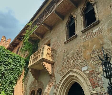 Balkon Julii w Weronie — słynna gotycka loggia w kamienicy Casa di Giulietta, pokryta częściowo bluszczem, na tle zabytkowej ceglanej fasady.
