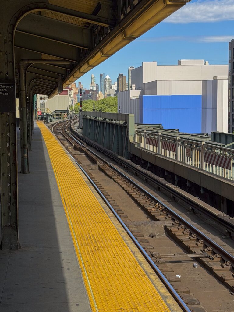 Peron stacji metra Queensboro Plaza w Nowym Jorku z torami prowadzącymi w kierunku Manhattanu